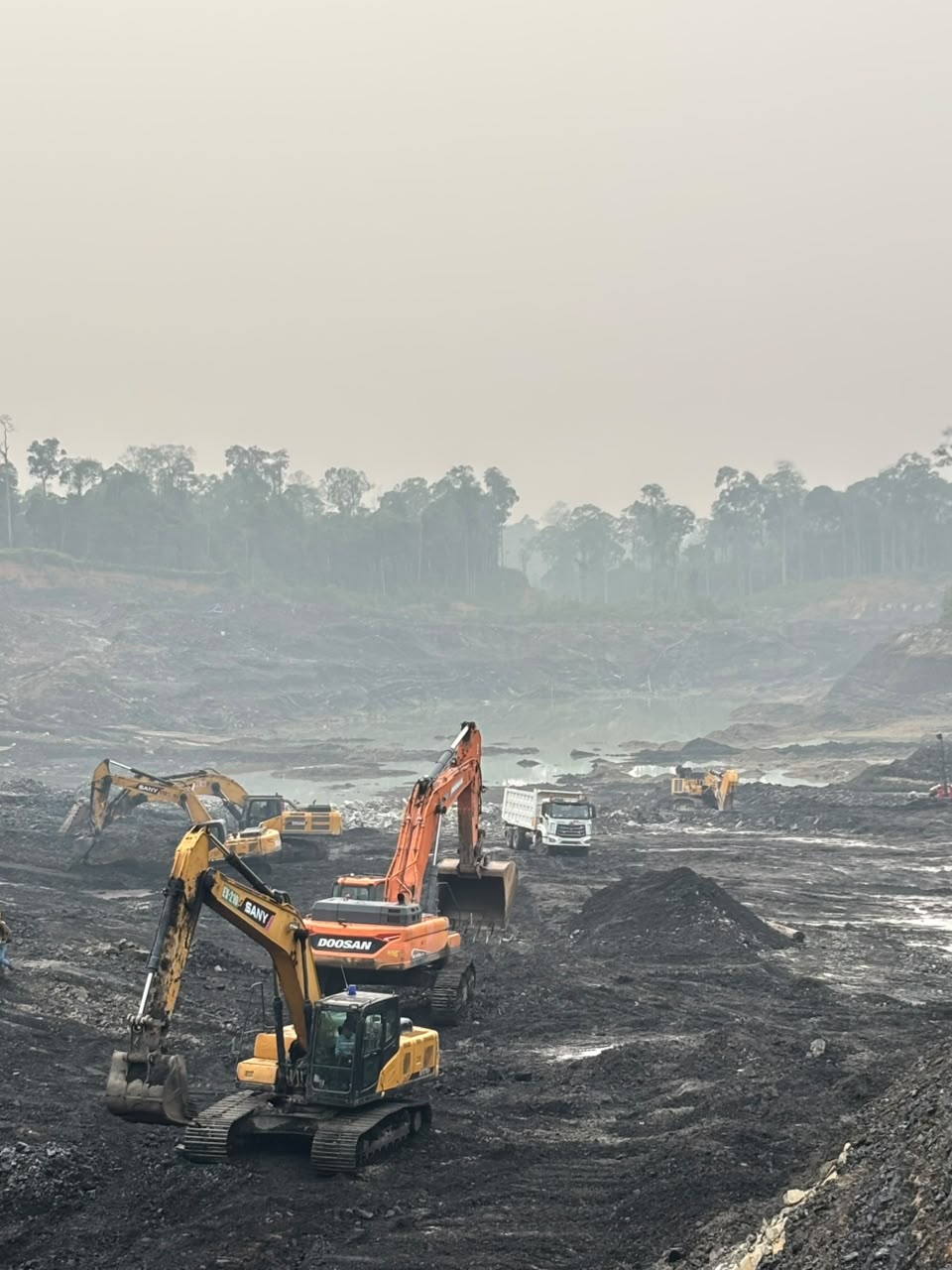 Beberapa excavator dan dump truck di area tambang terbuka